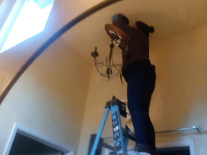 Electrician installing a chandelier in a Heath residence